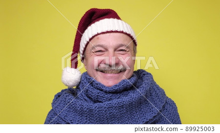 Senior man in a New Year cap smiling at camera. 89925003