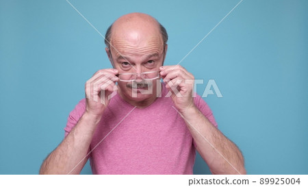 Senior hispanic man looking through glasses being shocked Senior hispanic man looking through glasses being shocked 89925004