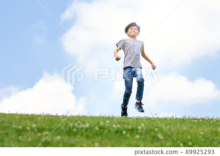 Elementary school boy running in the field against the background of the blue sky Elementary school boy running in the field against the background of the blue sky 89925293