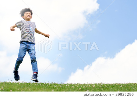 Elementary school boy running in the field against the background of the blue sky Elementary school boy running in the field against the background of the blue sky 89925296