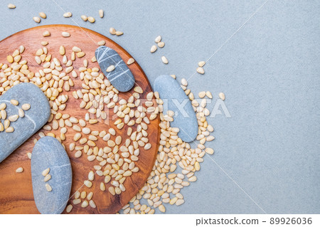 Oval gray stones on a wooden stand in a placer of Siberian cedar nuts. 89926036