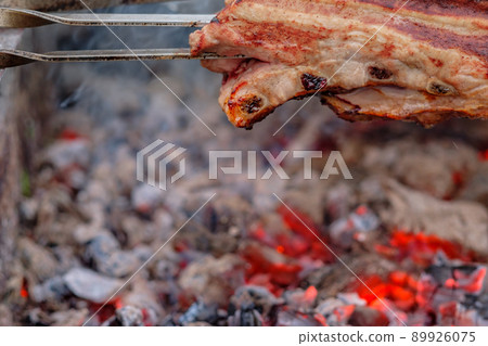 Juicy slices of pork meat are strung on skewers and grilled in charcoal grill. Juicy slices of pork meat are strung on skewers and grilled in charcoal grill. 89926075