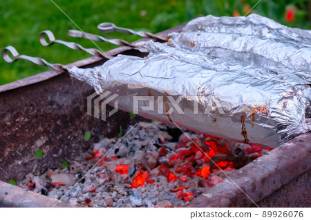 The meat on metal skewers is wrapped in aluminum foil and grilled on charcoal. The meat on metal skewers is wrapped in aluminum foil and grilled on charcoal. 89926076
