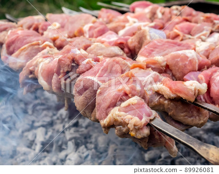 Juicy slices of pork meat are strung on skewers and grilled in charcoal grill. Juicy slices of pork meat are strung on skewers and grilled in charcoal grill. 89926081