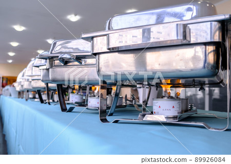 Flames from an alcohol burner under a brilliant stainless steel food warmer.Kitchen equipment of the restaurant. 89926084