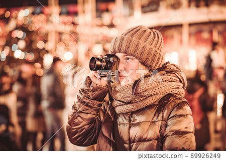 A young woman takes photos in the night city during the Christmas holidays. A young woman takes photos in the night city during the Christmas holidays. 89926249