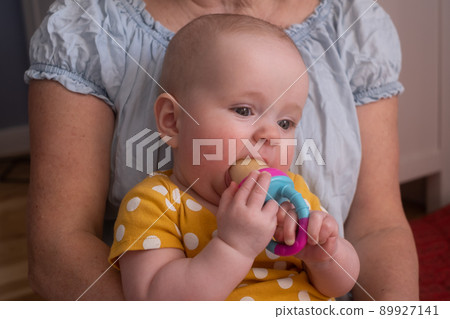 Seven month baby tasting apple with nibbler for firt time. 89927141