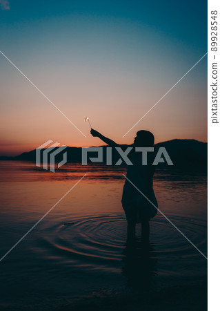 A silhouette of a woman in a dress and a beautiful sunset in a beautiful summer 89928548