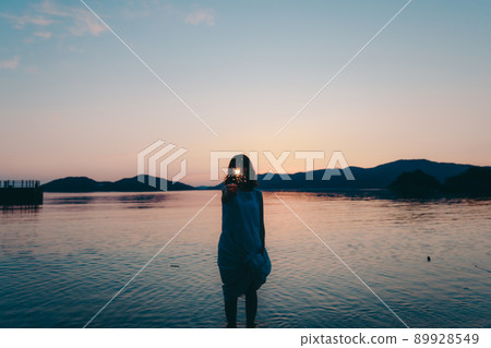 A silhouette of a woman in a dress and a beautiful sunset in a beautiful summer A silhouette of a woman in a dress and a beautiful sunset in a beautiful summer 89928549