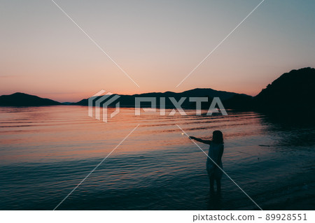 A silhouette of a woman in a dress and a beautiful sunset in a beautiful summer A silhouette of a woman in a dress and a beautiful sunset in a beautiful summer 89928551