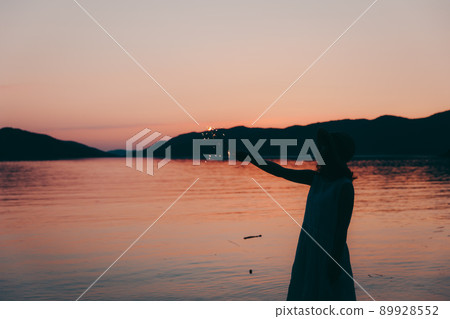 A silhouette of a woman in a dress and a beautiful sunset in a beautiful summer A silhouette of a woman in a dress and a beautiful sunset in a beautiful summer 89928552