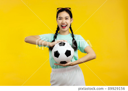 Portrait of Cheerful Asian woman holding a soccer ball isolated on yellow background, football sport concept 89929156
