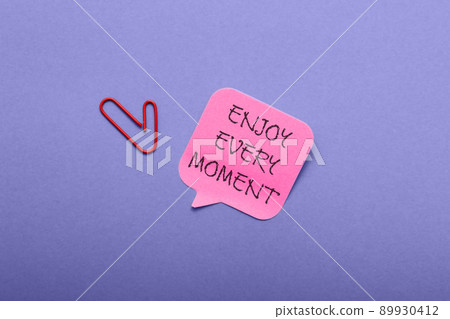 Paper with text Enjoy Every Moment on violet background Paper with text Enjoy Every Moment on violet background 89930412