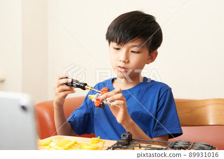 Elementary school boy assembling teaching materials using a screwdriver 89931016