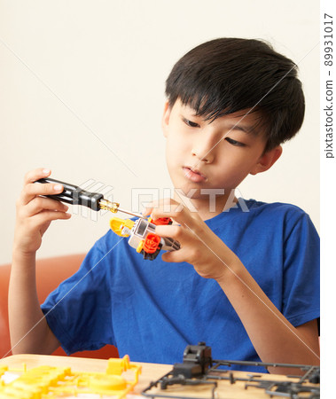 Elementary school boy assembling teaching materials using a screwdriver 89931017
