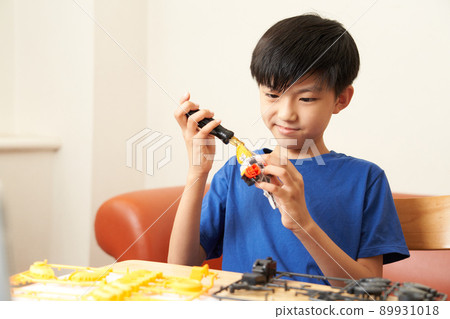 Elementary school boy assembling teaching materials using a screwdriver 89931018