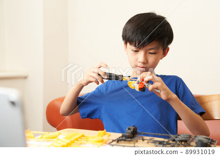 Elementary school boy assembling a model using a screwdriver 89931019