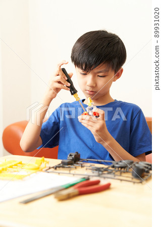 Elementary school boy assembling teaching materials using a screwdriver 89931020