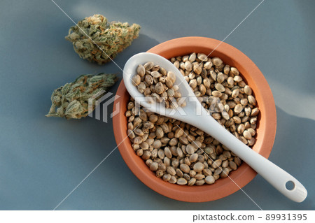 A bunch of cannabis seeds lie on a spoon and plate with several dried buds A bunch of cannabis seeds lie on a spoon and plate with several dried buds 89931395