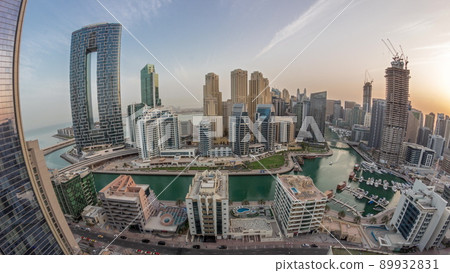 Dubai Marina with several boats and yachts parked in harbor and skyscrapers around canal aerial morning timelapse. 89932831