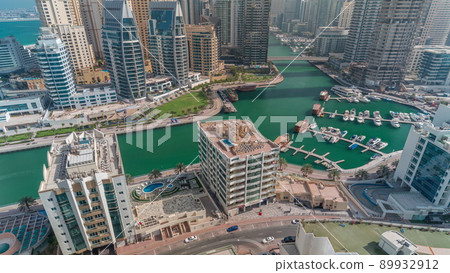 Dubai Marina with several boat and yachts parked in harbor and skyscrapers around canal aerial timelapse. 89932912