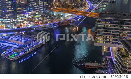 Aerial view to Dubai marina skyscrapers around canal with floating boats night timelapse 89933498