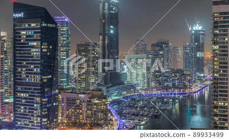 Aerial view to Dubai marina skyscrapers around canal with floating boats night timelapse 89933499
