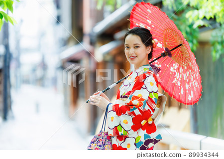 一個穿著和服的年輕女子拿著一把日本雨傘 89934344