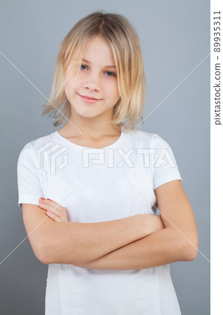 Cute child girl in white t-shirt smiling and standing with crossed arms 89935311