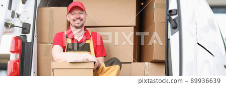 Man courier holding a parcel while sitting in the truck Man courier holding a parcel while sitting in the truck 89936639