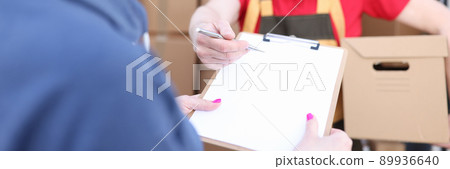 Courier holds parcel, woman signs document Courier holds parcel, woman signs document 89936640
