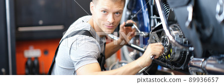 Male mechanic in a garage repairing a motorcycle Male mechanic in a garage repairing a motorcycle 89936657