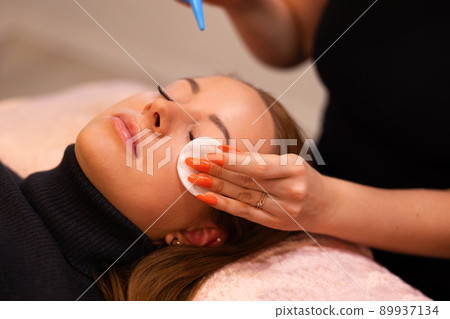 Hands Of Beauty Specialist Rubbing Cotton On Female Client's Face 89937134