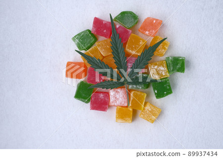 Layout of colorful marmalade and marijuana leaf on white textured background Layout of colorful marmalade and marijuana leaf on white textured background 89937434