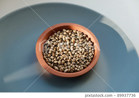Cannabis seeds close-up. Marijuana seeds with storage jar on blue background Cannabis seeds close-up. Marijuana seeds with storage jar on blue background 89937736