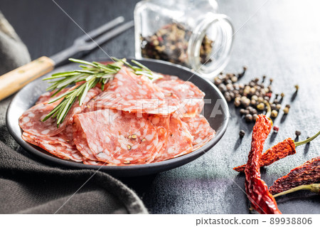 Sliced italian salami sausage with peppercorn on plate. 89938806