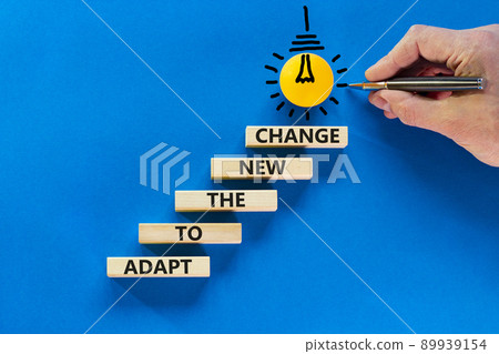 Adapt to the new change symbol. Wooden blocks with words Adapt to the new change on blue background, copy space. Light bulb icon. Businessman hand with pen. Business, adapt to change concept. 89939154