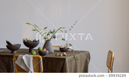 Elegant table setting with green brunches in craft vase , cherimoya fruits, brown champignons, eggplants in craft ceramic plate on linen tablecloth. Outdoor table setting for summer holiday concept. 89939289