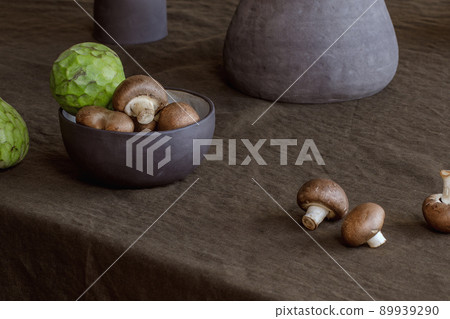 Elegant table setting with cherimoya fruits, brown champignons in craft ceramic plate on linen tablecloth. Outdoor table setting for summer holiday concept. 89939290