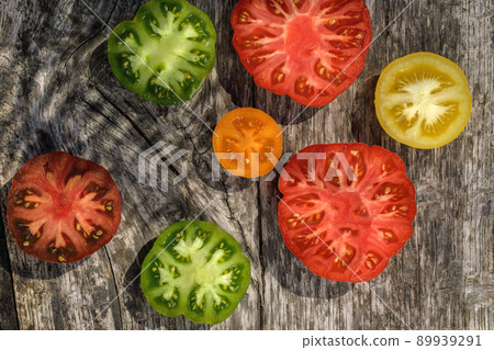 Variety of ripe organic tomatoes of different colours on aged wood background. Garden season and healthy eating concept 89939291