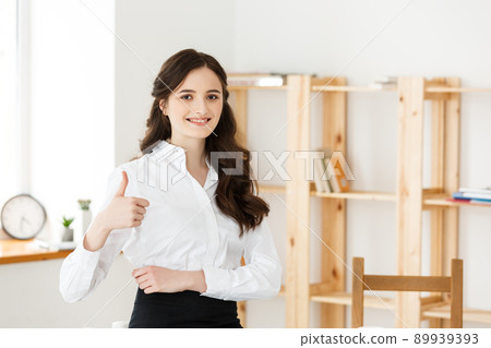 Attractive young female showing thumbs up in an office Attractive young female showing thumbs up in an office 89939393