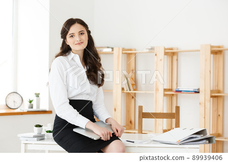 Happy young business woman or secretary holding laptop in modern office 89939406