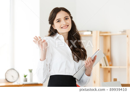 Happy young business woman or secretary holding document in modern office Happy young business woman or secretary holding document in modern office 89939410
