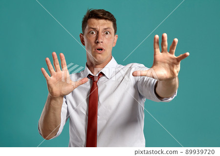 Young man in a classic white shirt and red tie posing over a blue background. Young man in a classic white shirt and red tie posing over a blue background. 89939720