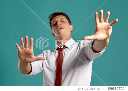 Young man in a classic white shirt and red tie posing over a blue background. Young man in a classic white shirt and red tie posing over a blue background. 89939721