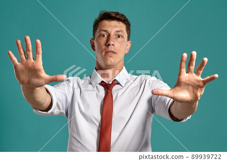 Young man in a classic white shirt and red tie posing over a blue background. Young man in a classic white shirt and red tie posing over a blue background. 89939722