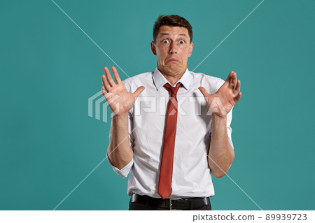 Young man in a classic white shirt and red tie posing over a blue background. Young man in a classic white shirt and red tie posing over a blue background. 89939723