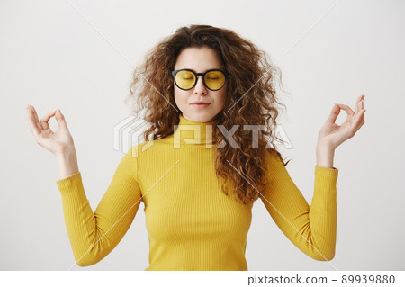 Portrait calm woman smiling doing yoga exercises relaxing on white blank studio wall, happy young girl meditating feeling no stress. Portrait calm woman smiling doing yoga exercises relaxing on white blank studio wall, happy young girl meditating feeling no stress. 89939880