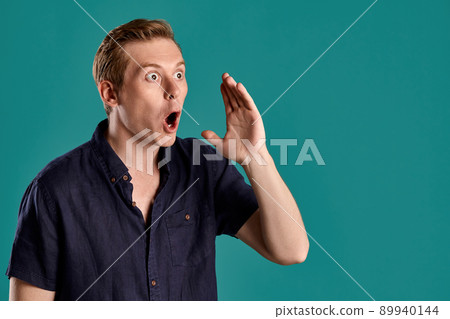 Close-up portrait of a ginger guy in navy t-shirt posing on blue background. Sincere emotions. Close-up portrait of a ginger guy in navy t-shirt posing on blue background. Sincere emotions. 89940144
