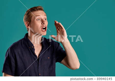 Close-up portrait of a ginger guy in navy t-shirt posing on blue background. Sincere emotions. 89940145